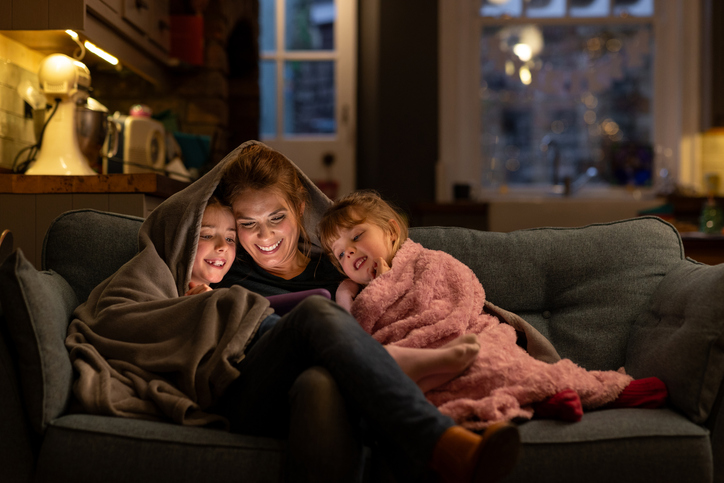 Mom & kids sitting under a blanket on the couch 