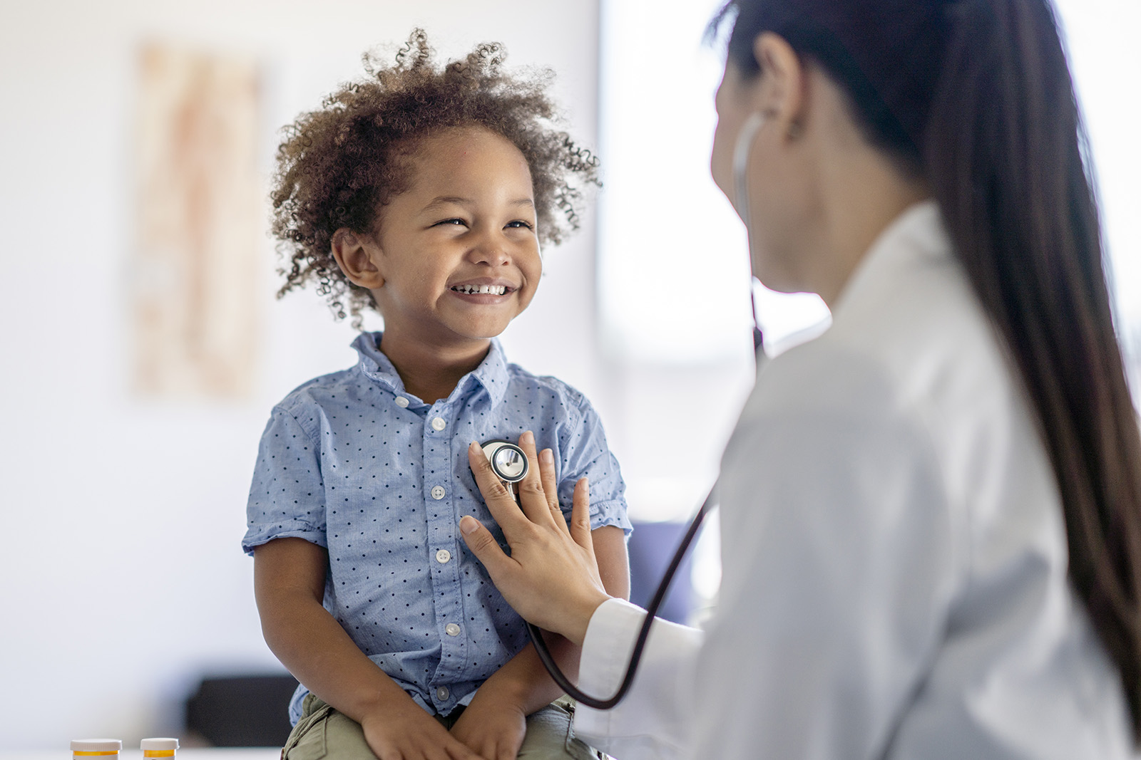 child smiling at his pediatric provider during a well visit