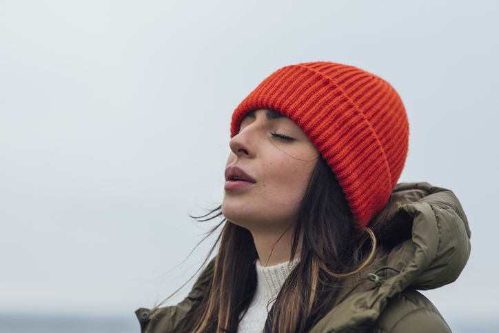 Woman in winter hat taking deep breath