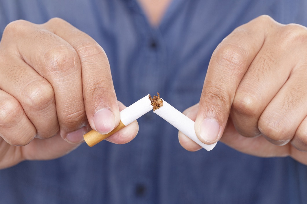 Hands break cigarette in half