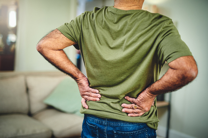 Man standing and holding his back as if he is in pain