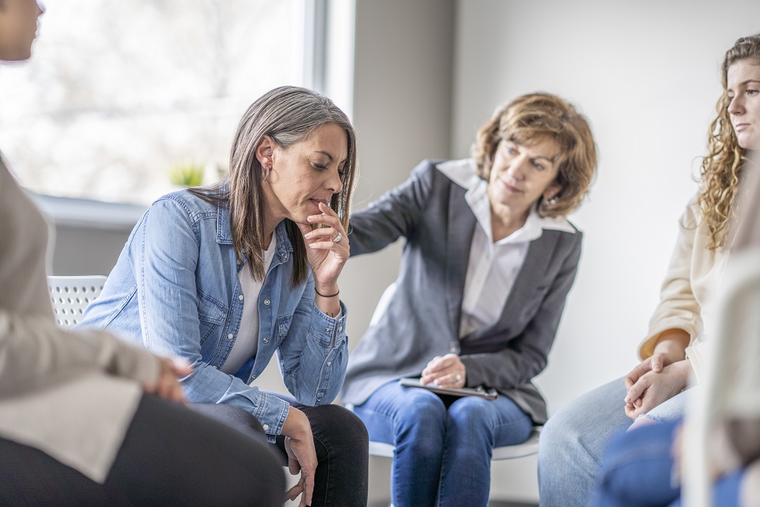 A listener pats the shoulder of a woman during a caregiver support group