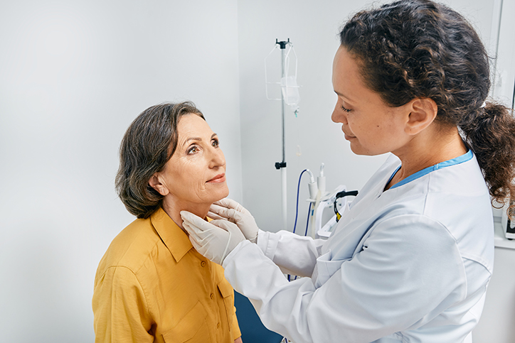 Doctor checks woman's neck for diagnostics of thyroid diseases and hypothyroidism at medical clinic