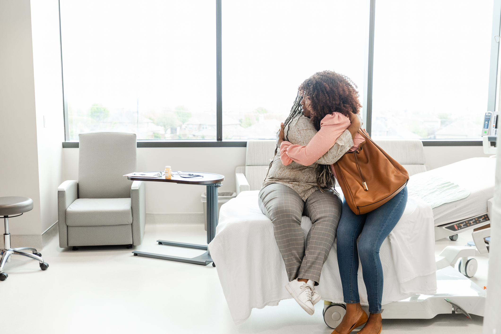 Two people hug inside of a hospital room