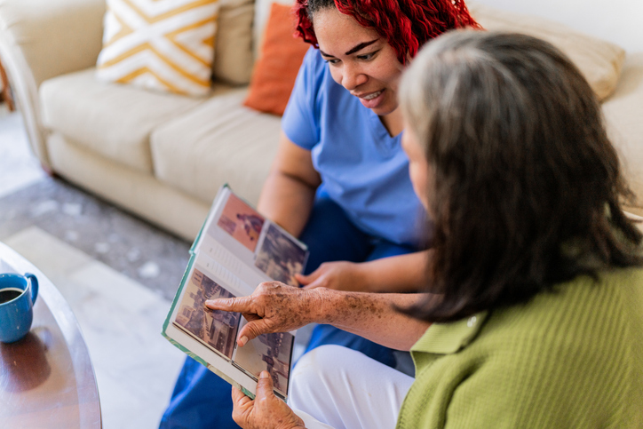Caregiver in a memory care facility looking at a photo album with a patient