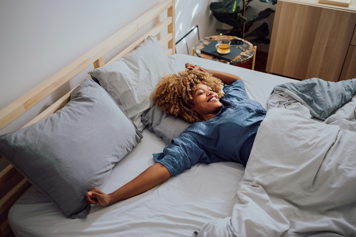 Woman stretches in bed as she wakes up
