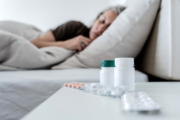 woman lying in her bed with sleep aids on the nightstand