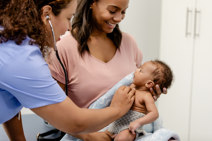 Mom Holding Baby Being Examined by Doctor