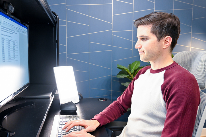 Man sits at desk using at-home light therapy lamp
