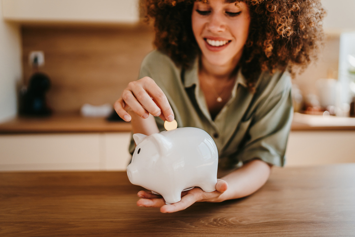 Woman Putting Money in a Piggy Bank