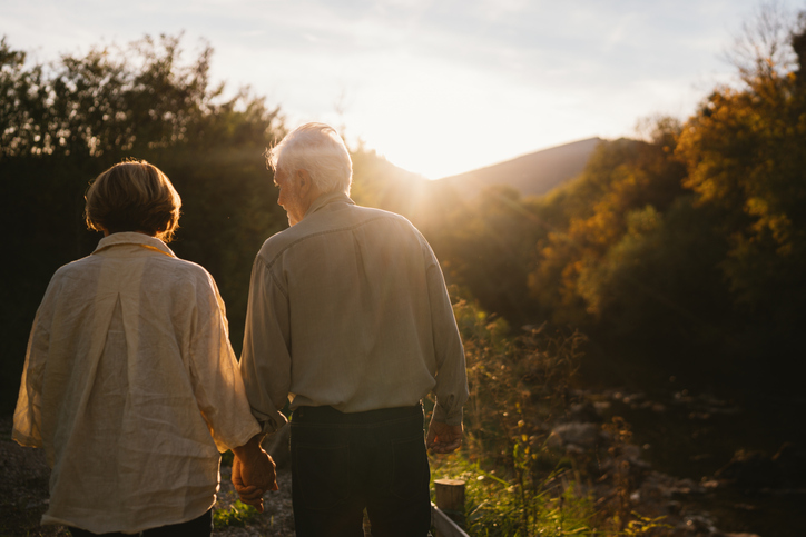 Couple walk hand-in-hand through nature