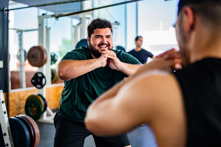Mid-sized man smiling as he exercises with a trainer