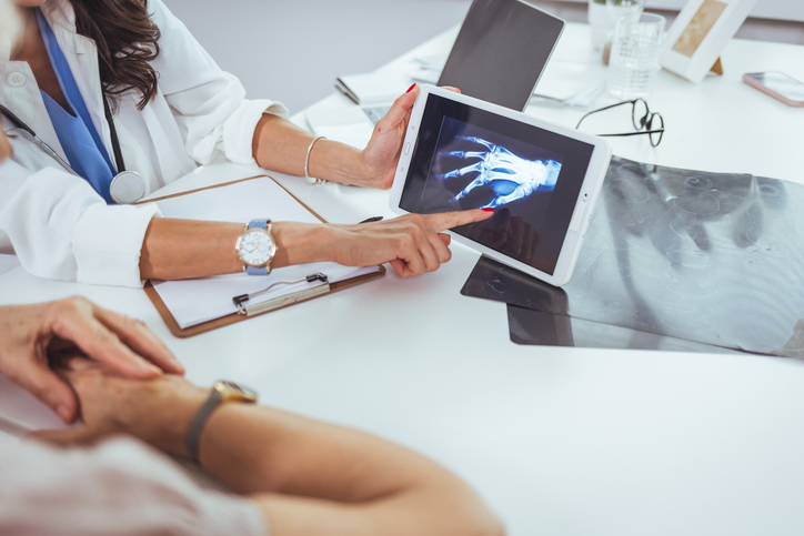 Doctor and patient looking at x-ray and hand in doctor's office.