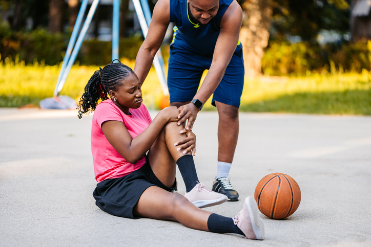 A woman holding her knee after an injury on the basketball court