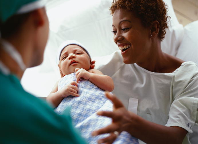 Woman being handed baby by doctor