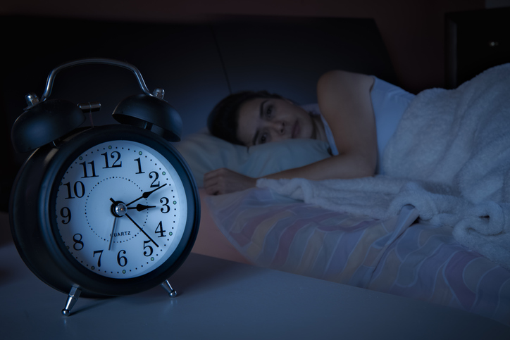 Alarm clock sits next to sleeping woman