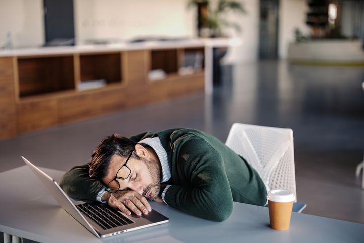 Tired office worker with head down on desk, experiencing fatigue at work