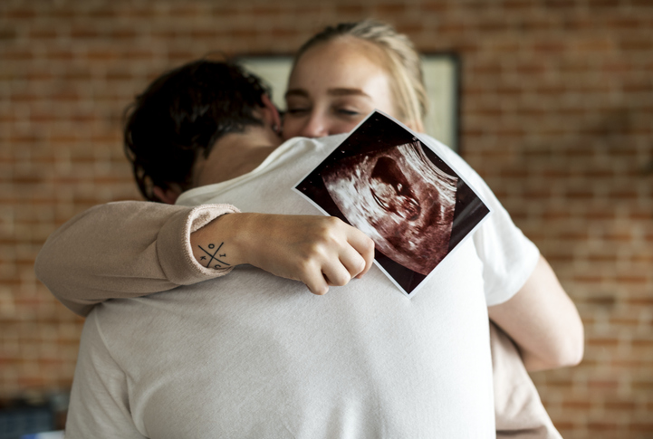 Couple with sonogram hugging
