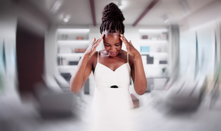 A woman holding her head, experiencing dizziness, a sign of stroke