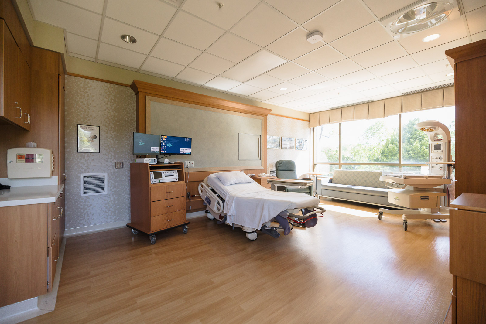 Private labor and delivery suite with patient bed, family seating, and large windows.
