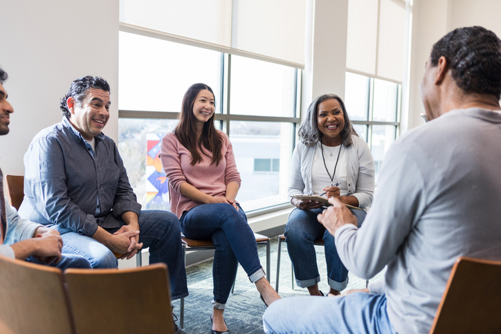 A group of people chat in a support group