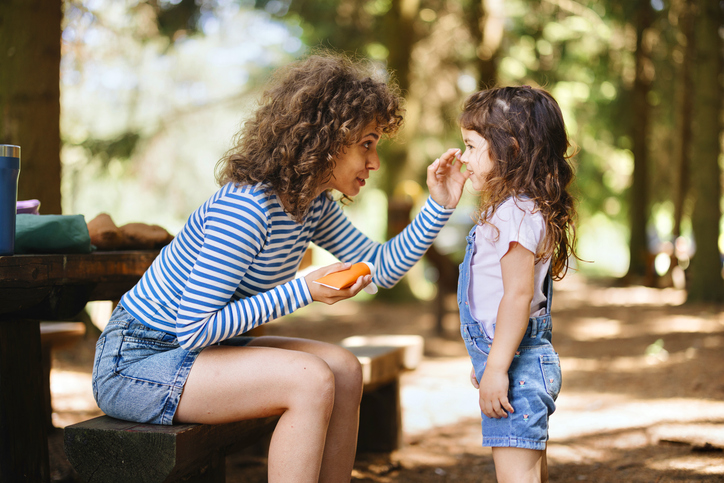 Mother applies sunscreen to daughter's face