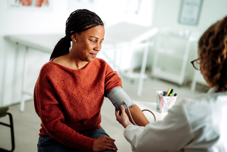 Woman having blood pressure checked by female doctor