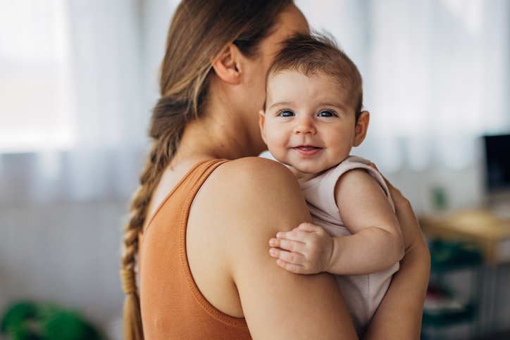  A mother with braided hair holds her cute baby daughter in her arms