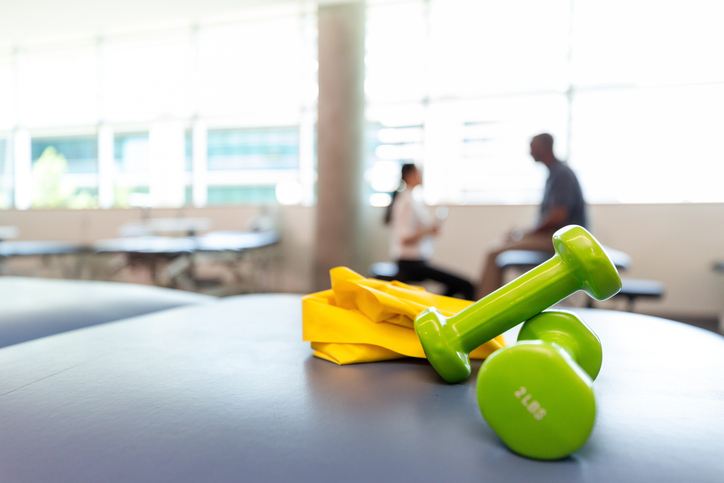 Green dumbbells and yellow resistance band for physical therapy and rehabilitation