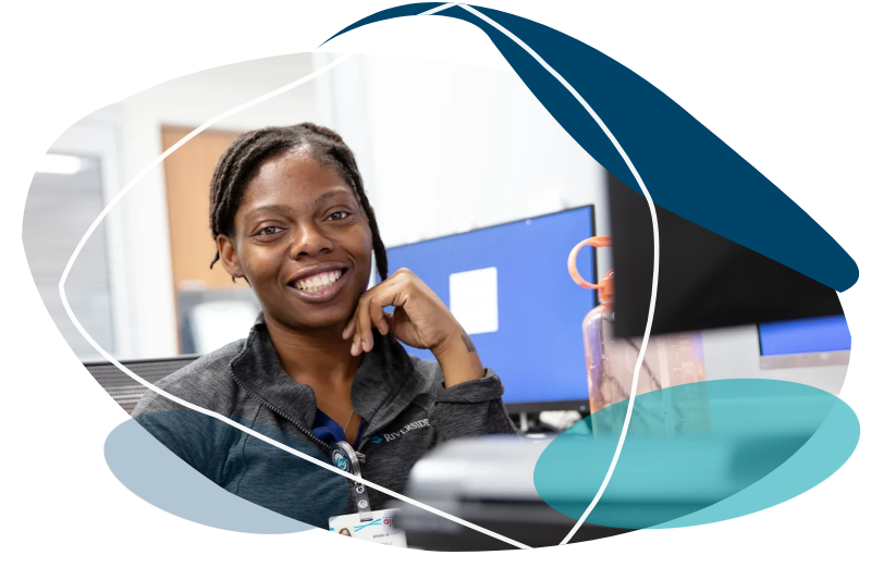 Smiling Riverside Healthcare worker at a clinic desk.