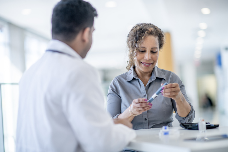 A woman discusses diabetes screening, blood glucose testing, and healthy habits with an endocrinologist during a medical appointment.