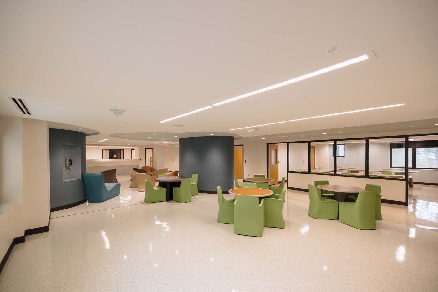 Group and recreation space with soft green seating and large windows in the new behavioral health unit.
